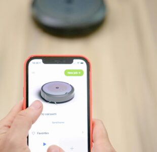 pexels-photo-8566440-8566440 User operates robotic vacuum via smartphone app, showcasing smart home technology.